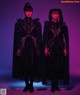 A couple of women standing next to each other in black dresses.