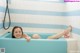 A woman laying in a bathtub with her feet up in the water.