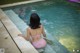 A woman in a pink bikini sitting in a swimming pool.