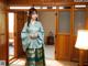 A woman in a blue and green kimono standing in a room.